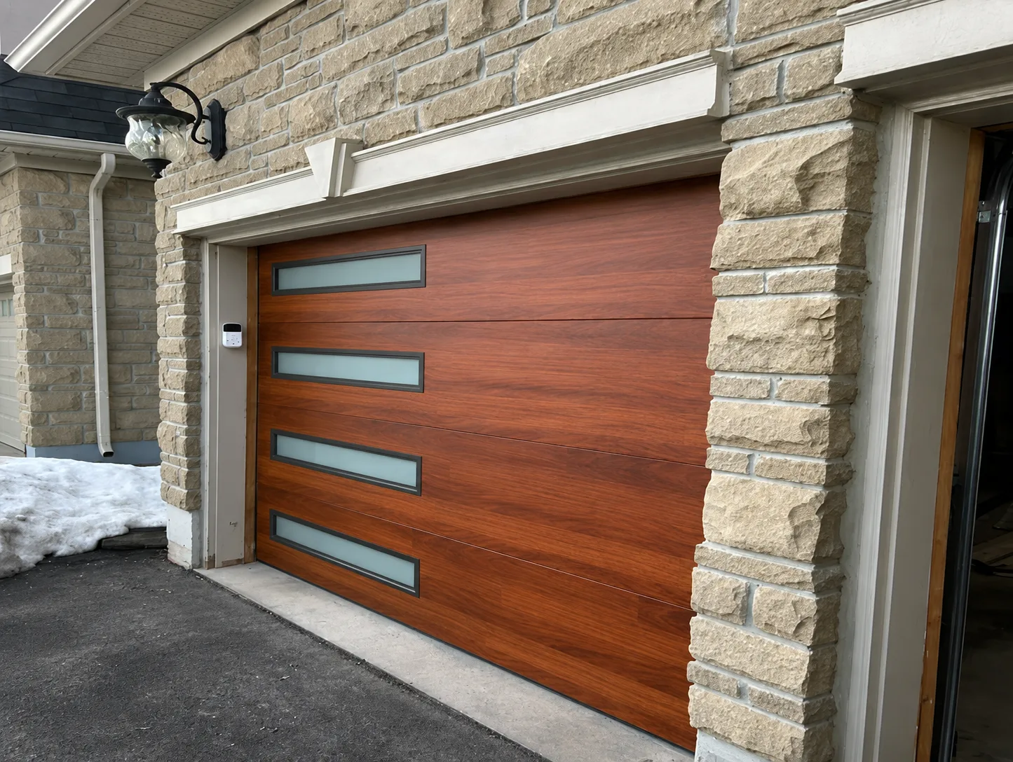 Residential sectional garage door with wood finish and narrow windows.